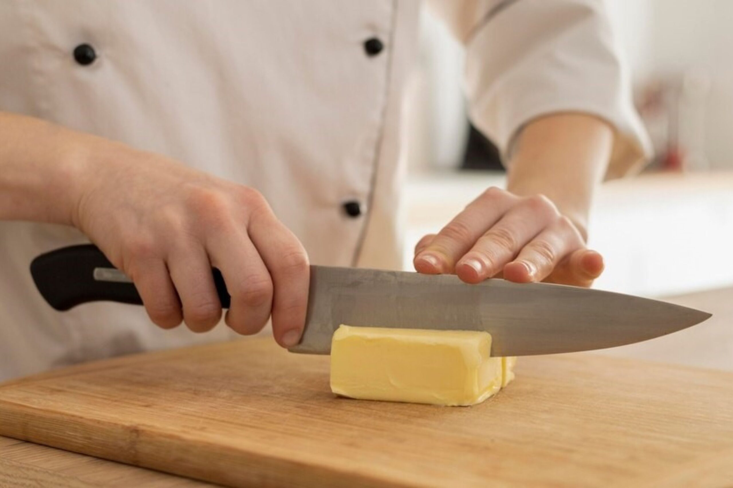 Cook cutting Butter with a chef knife on a board