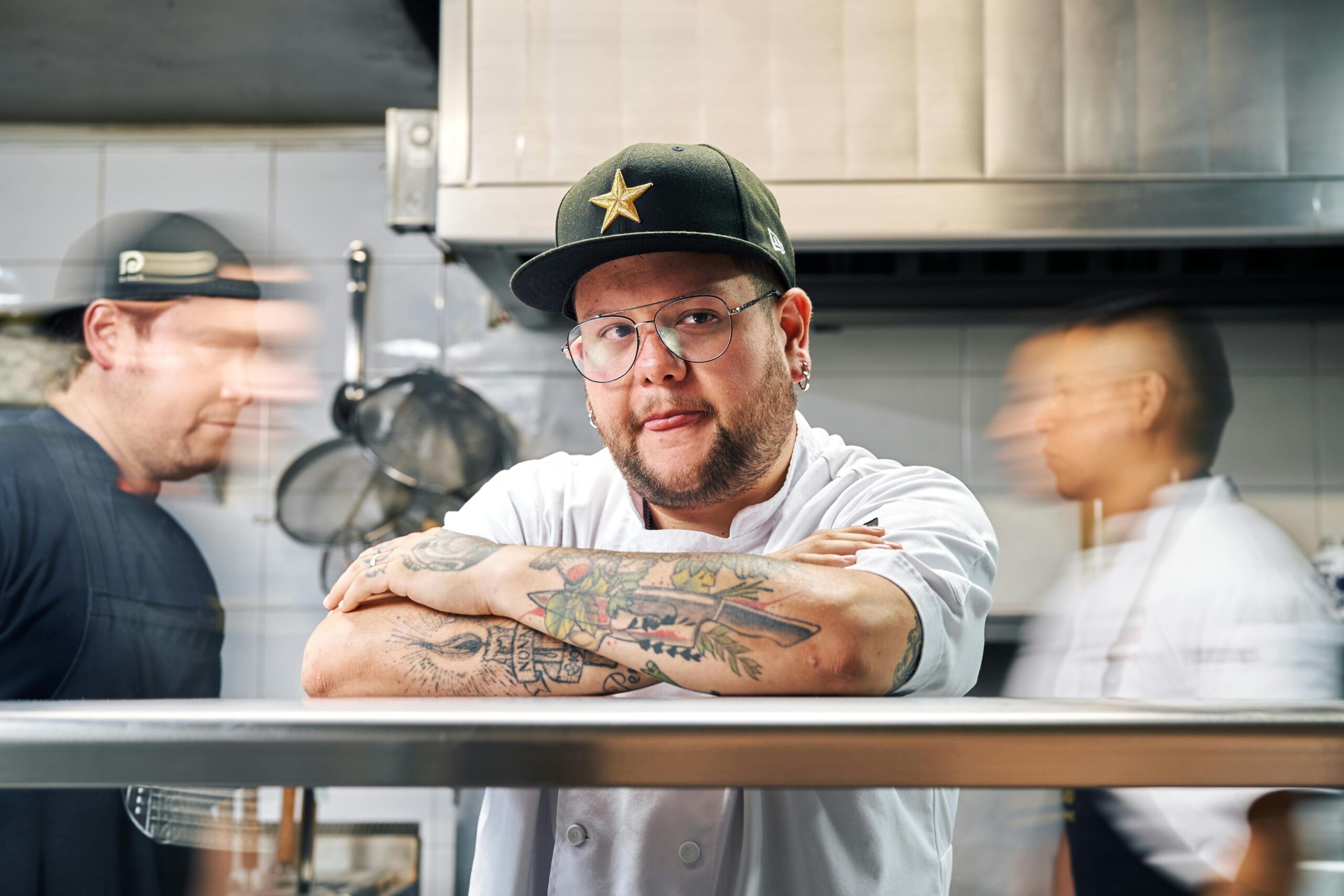 professional chef with tattoos on his arms on the pass in the kitchen
