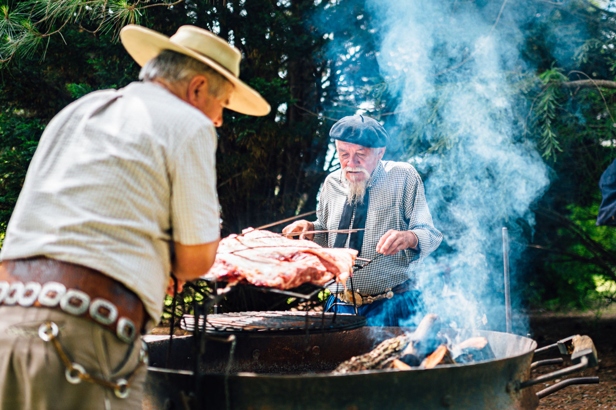 Traditional uruguayan asado meat grilling on parrilla with smoke and flames