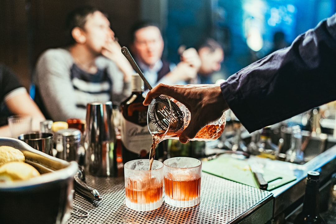 A bartender serves a premium spirit sample at the Food Festival, surrounded by enthusiastic visitors at an outdoor event.