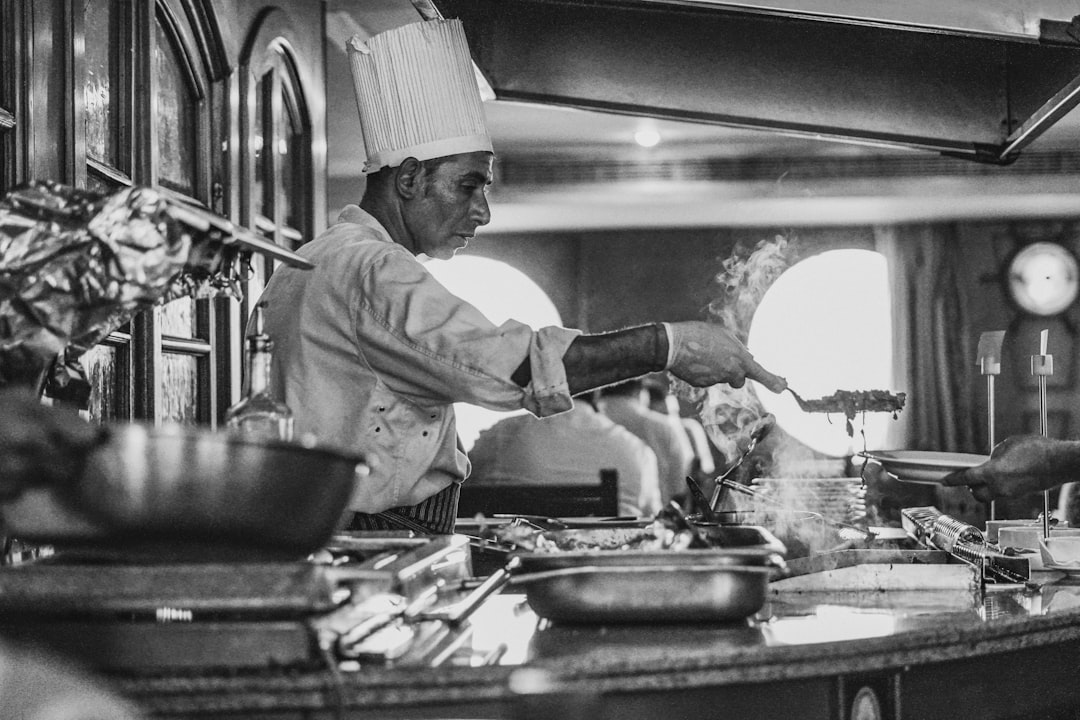A professional chef stirs a deep pot of Neapolitan ragù over a low flame in a traditional kitchen