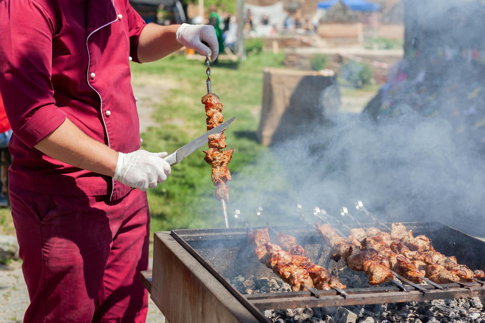 A professional chef arranges serving dishes at an outdoor catering station during a large off-site event.