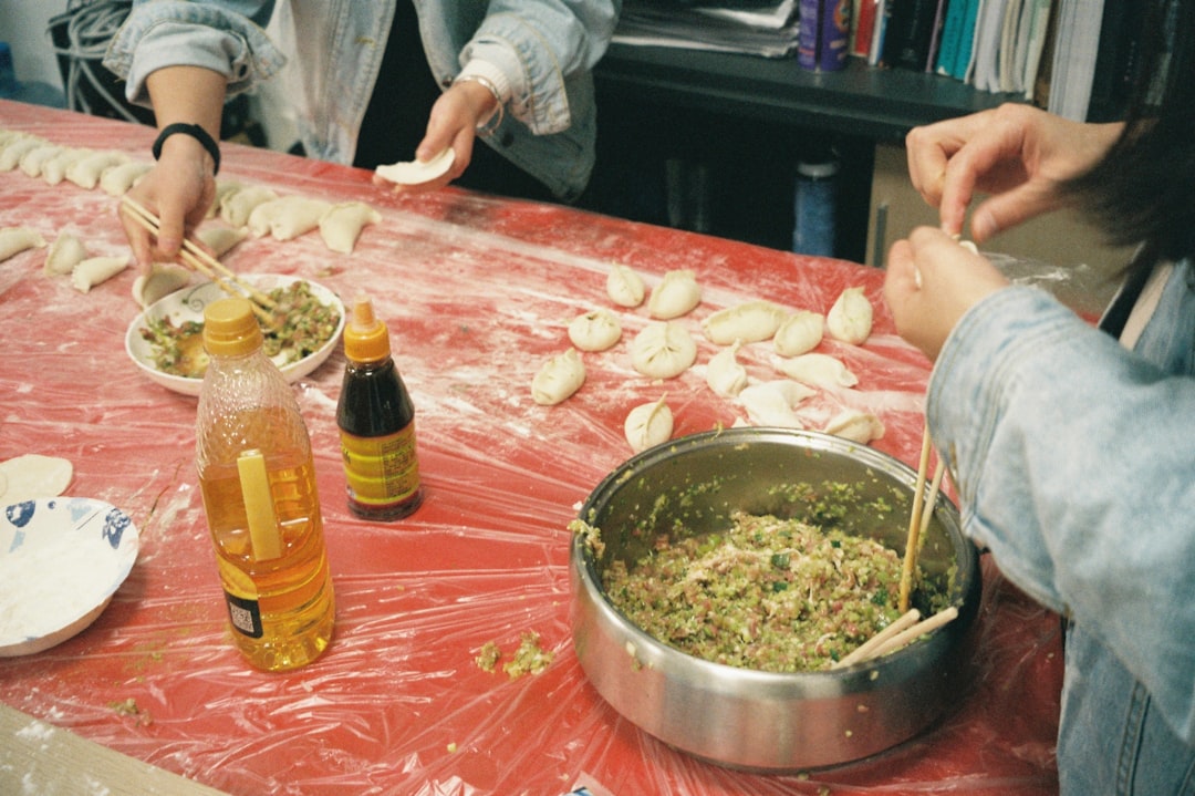 A woman folding handmade dumplings on a floured wooden surface, demonstrating the traditional craft behind this beloved dish