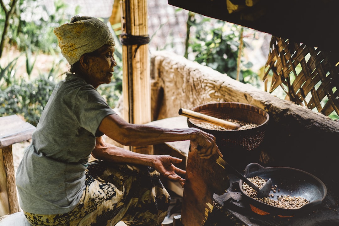 A woman carefully grinding aromatic spice blends from Africa using a traditional stone mortar and pestle in a home kitchen