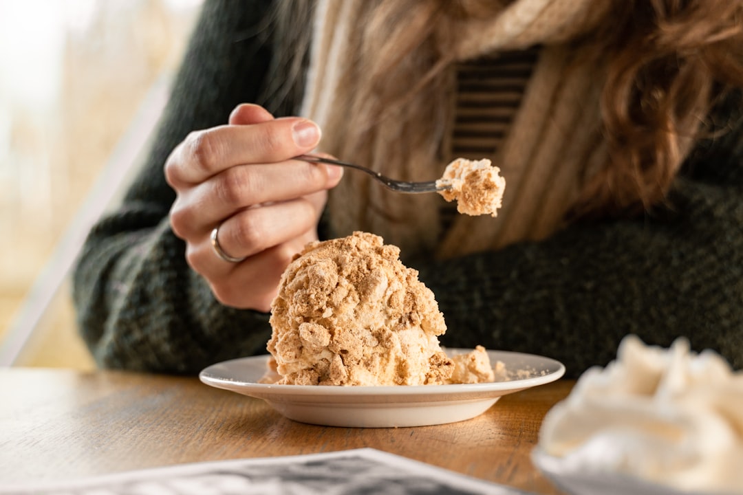 A woman scooping a bowl of homemade ice cream from a metal loaf pan in a bright kitchen