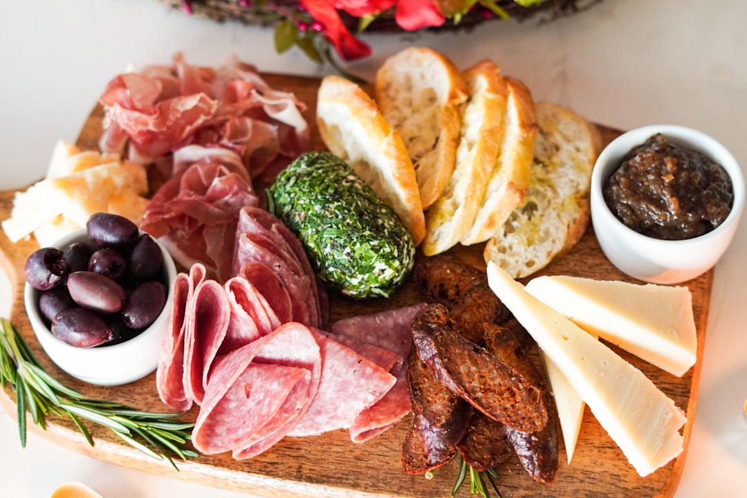 a colorful summer grazing board with global pantry staples including cured meats, cheese, and fresh fruit on a wooden surface