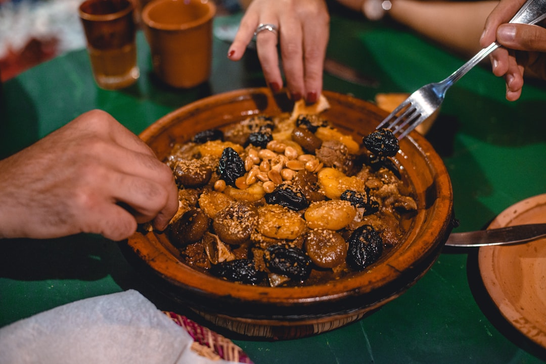 A spice vendor in Marrakech souk surrounded by colorful Moroccan cuisine ingredients