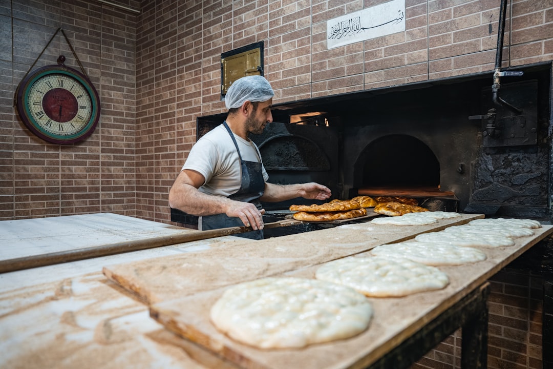 A man pressing flatbreads against the wall of a traditional clay oven, demonstrating the ancient craft of flatbread making.