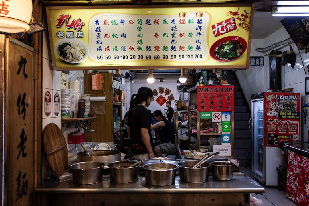 A woman carefully ladling street food pho broth into a bowl at a home kitchen counter