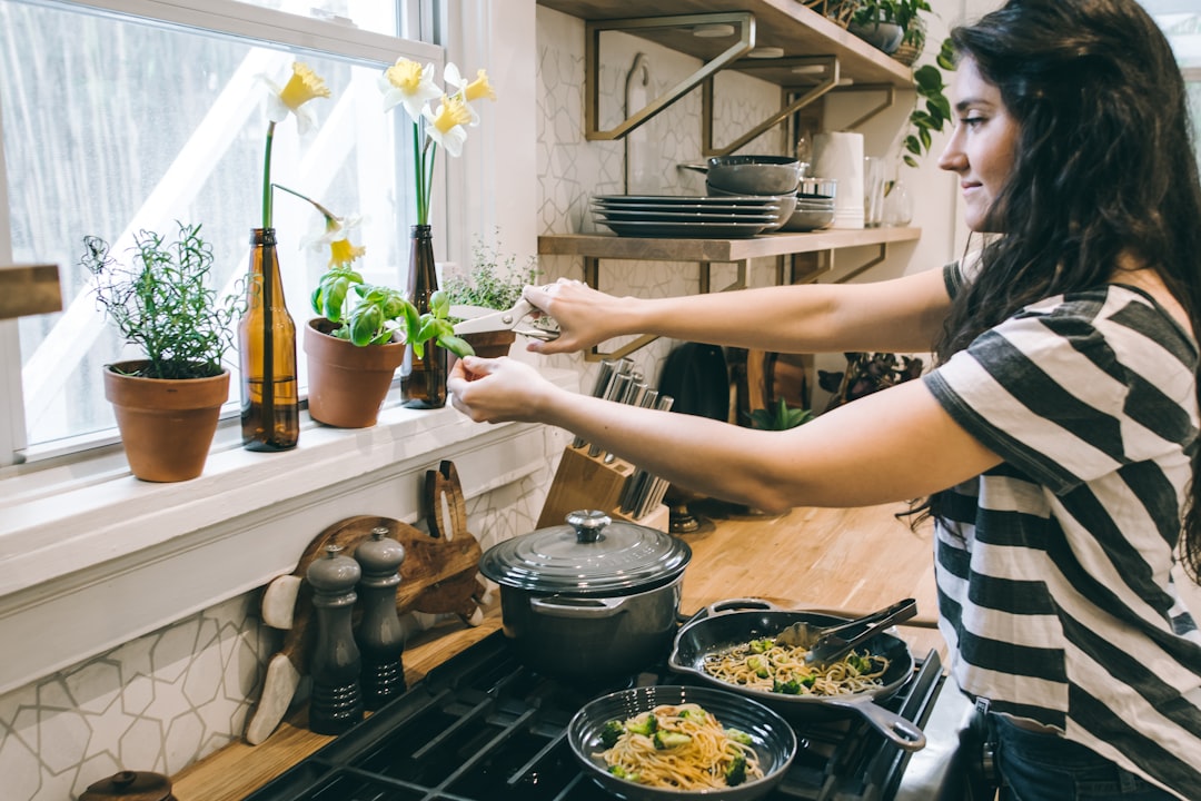 A woman applies a thin layer of oil to a cast iron pan during the cast iron seasoning process in a home kitchen.