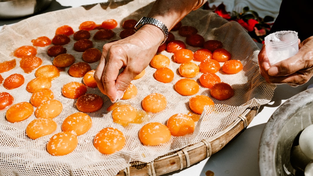 A pastry chef arranging halved apricots into a frangipane tart shell, showcasing the craft of stone fruit dessert preparation