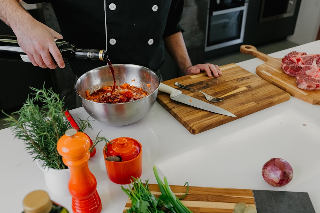 A chef whisking together marinade basics including oil, citrus, and fresh herbs in a large ceramic bowl