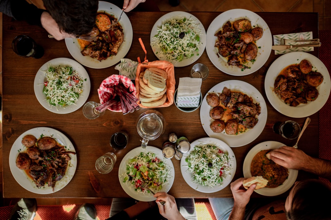 A group of guests reaching across a communal table covered in shared dishes, celebrating the communal table tradition.