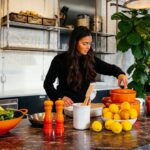 a woman arranges roasted root vegetables on a plate as part of the new autumn menus service in a kitchen.