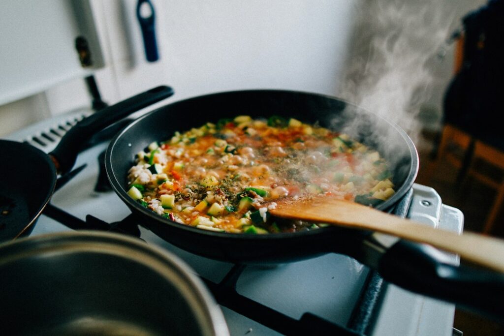A professional chef making a pan sauce by deglazing a hot skillet with wine in a restaurant kitchen