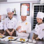A chef presents a plate at an international culinary congress, like San Sebastian Gastronomika.