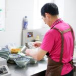 A chef carefully building an aromatic base in a pot, preparing a classic one-pot rice dish with layered spices and stock.