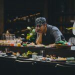 A hotel dining team member tastes a new dish during a pre-service training session, building ingredient knowledge.