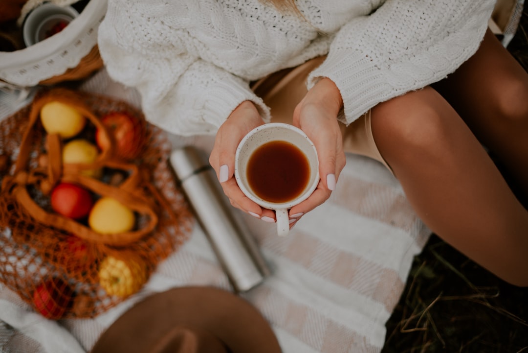 A woman cradles a ceramic mug of warm spiced drinks beside autumn leaves, showing the seasonal comfort of drink traditions.