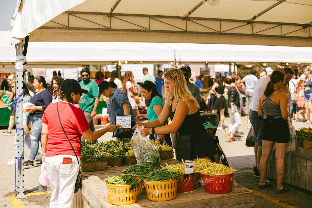 A woman selects seasonal vegetables at harvest markets in Europe during September, with crates of fresh produce arranged.