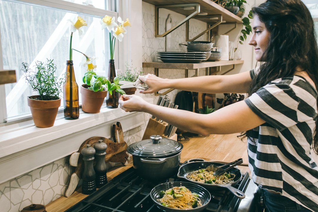 A home cook carefully stirring a warm grain dish in a large pot, surrounded by seasonal root vegetables on a kitchen counter